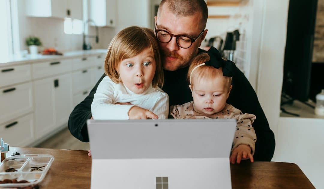 A father and two children sharing a surface laptop at home